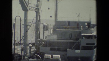 1981: ship sailing on the ocean and flags flying high. SAN DIEGO NAVAL BASE