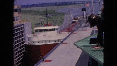 1964: a young girl and an elderly man looking at boats from the dock.