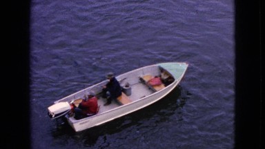 1964: two people driving a small boat in still water seems to be fishing