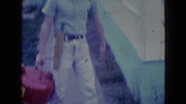 1965: Boy Walking on Sidewalk Waving in Wellsburg, Iowa