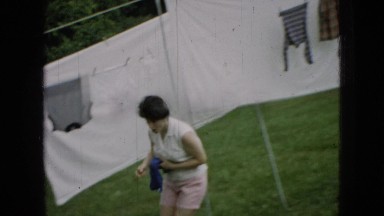 1965: woman sorting and hanging laundry on a clothes line outside WELLSBURG IOWA