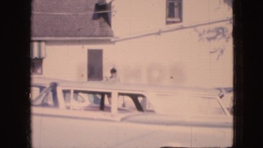 1967: woman walking out of her house toward the camera. IOWA