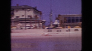 1968: a complete view of a beach with a pier and people swimming in the water