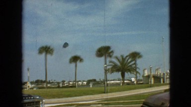 1968: a car driving down the street in a tropical setting with palm trees