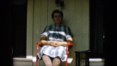 1957: a woman in a dress sitting on a red chair on the front porch PENNSYLVANIA