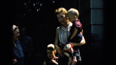 1957: mother and her kids all standing outside talking with the family.