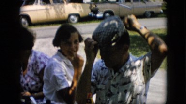 1957: people on beach sandwich maker putting ketchup hat car parked green grass