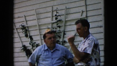1957: two men standing talking something serious backyard wearing shirt