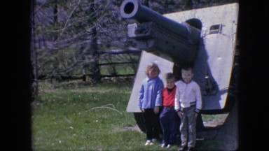 1964: three little children in a field running away in terror, big cannon