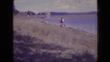 1964: man walking and putting down his shoes to pull up his rolled pants