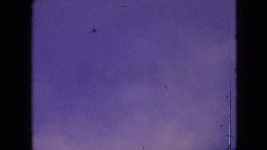 1964: a man standing alone out in a field flying a kite in a cloudy sky