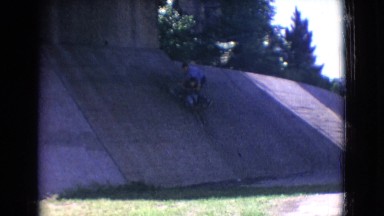 1965: brother helping little brother climb a slanted wall underneath a bridge