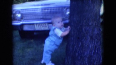 1966: cute boy baby standing near the car and holding the tree. ATHENS OHIO