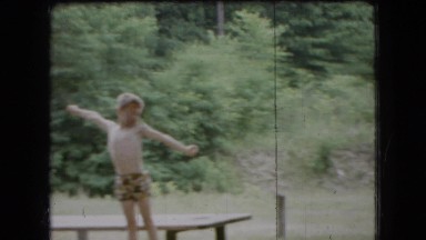 1966: a child clowning around on the picnic table while his mother looks on.