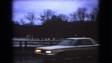1966: cars driving by a bridge, water way, raining night time