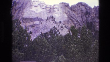 1974: man viewing and photographing mount rushmore, surrounding hills