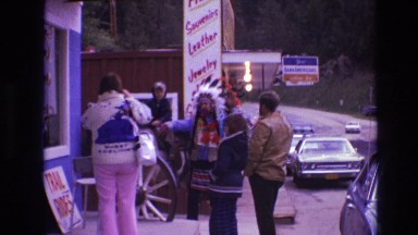 1974: man in american indian headdress being photographed with little boy