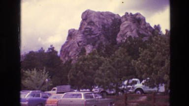 1974: many cars parked moving road trees all over clear sky cloudy day