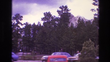 1974: parking lot view of mt. rushmore peeking out above forest treeline