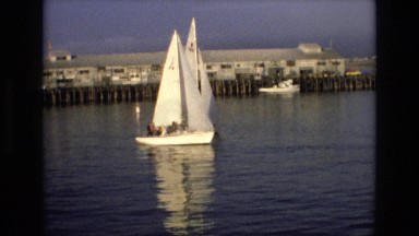 1965: beautiful sailboats moving over calm water away from the harbor