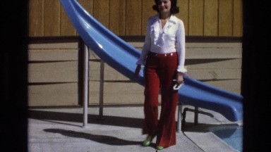 1965: woman wearing red belle bottom pants walks past blue slide CENTRAL COAST
