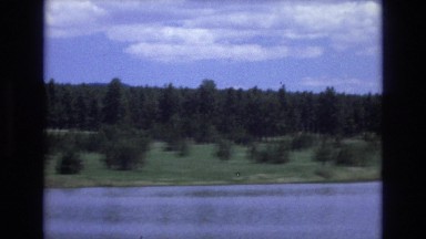 1966: ridge of trees behind a wide river with snow covered mountain range