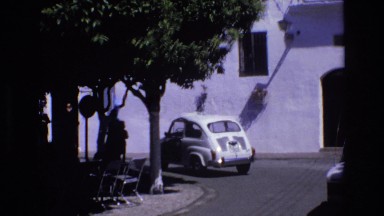 1969: car moving children uniform walking down the street trees around chairs