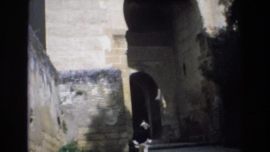 1969: people walk under the stone arch of an old building. SPAIN