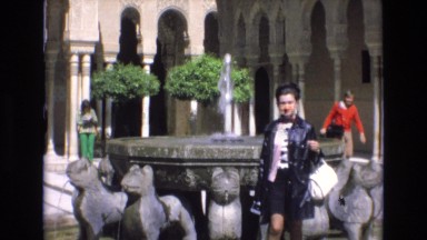 1969: black and white woman approaches from fountain with statues. SPAIN