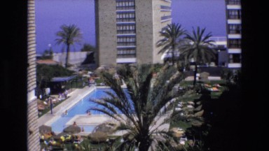 1969: A Body of Blue Water Next to a Tall Hotel in a Pretty Area Spain