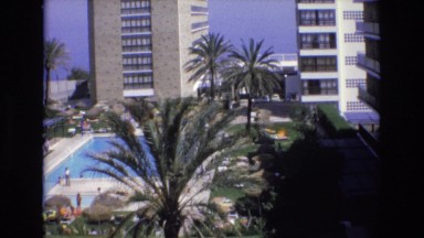 1969: People Walk Along Hotel Pool Deck on a Sunny Day in Spain
