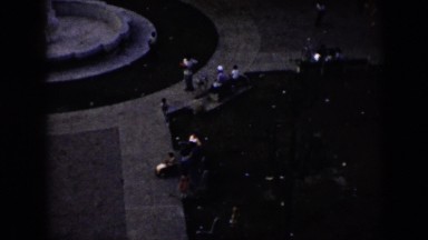 1956: a city park sculpture in a fountain like circle with people moving around