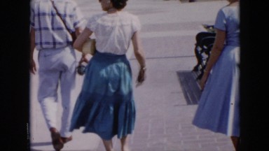 1956: two ladies and a man are walking down a sidewalk away from the camera