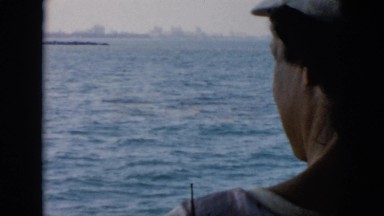 1956: man, woman and child on boat approaching city CUBA