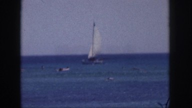 1961: people swimming in the ocean as a sailboat goes by HAWAII
