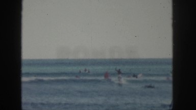 1961: dozens of people swimming and surfing at the beach HAWAII