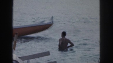 1961: a man impressed how another man can row a very large boat on the water.