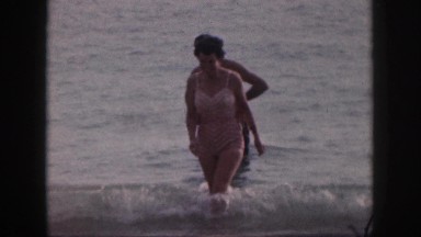 1961: a couple wading in the ocean head back toward the shore to sit down