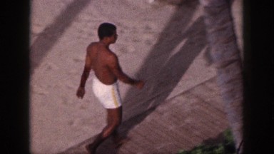 1961: man walking topless along garden area HAWAII