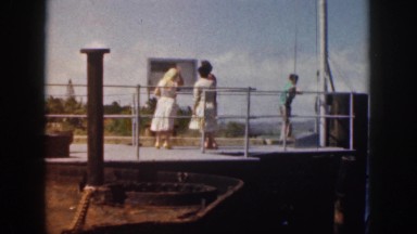 1961: naval officer in white uniform speaks to boy at pier railing