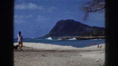 1961: female walking sea shore with pet dog wind blowing beautiful sight beach