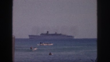 1961: a large ship cruises near shore as swimmers swim close to the beach HAWAII