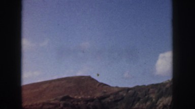 1961: beautiful waves crashing onto a red cliff under a clear sky. HAWAII