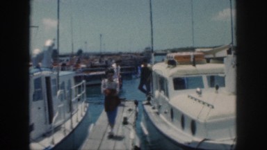 1961: harbour scene with docks small boats in the water with people moving out