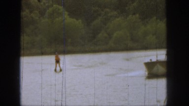 1961: man in drives motor boat and woman is behind him on a jet ski. MICHIGAN