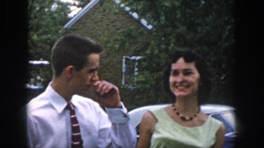 1958: a young man and a young woman nervously socialize outdoors near a car