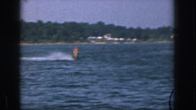 1961: man water skiing making waves on the lake on a nice hot summer day