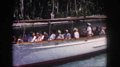 1958: a white boat turning with passengers in the blue water of the lake