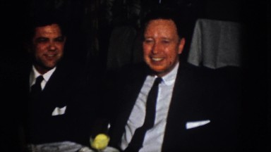 1958: two men sit at a table smiling and talking VIRGINIA