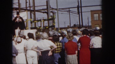 1958: people gathered around construction site black robe men giving safety